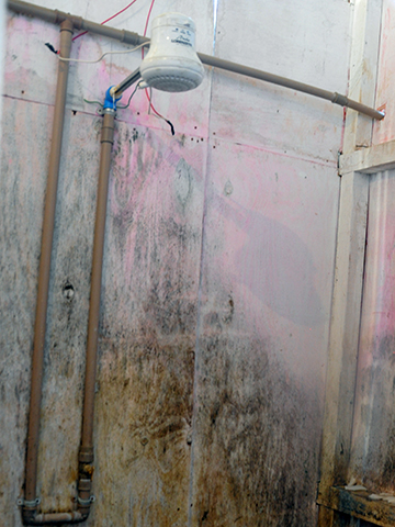 Chuveiro improvisado no abrigo em que o grupo estava alojado; fiação exposta oferecia riscos