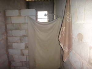 Banheiro improvisado de uma das casas, com divisória de lençol (Foto: SRTE-SP)