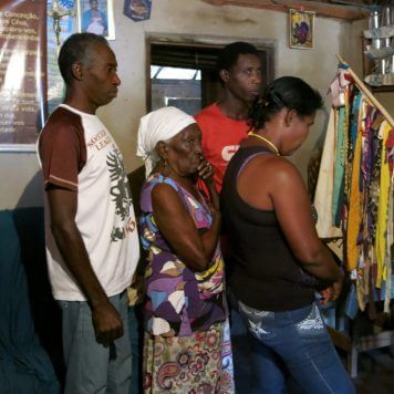 Alvina, filhos e sobrinha diante da bandeira de São Sebastião