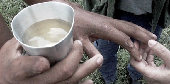 Trabalhador libertado mostra água que bebia, a mão machucada por falta de luvas na aplicação de pesticida e o dedo que perdeu na produção 