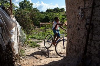 Criança de bicicleta no quintal da casa. Foto: Lilo Clareto/Repórter Brasil