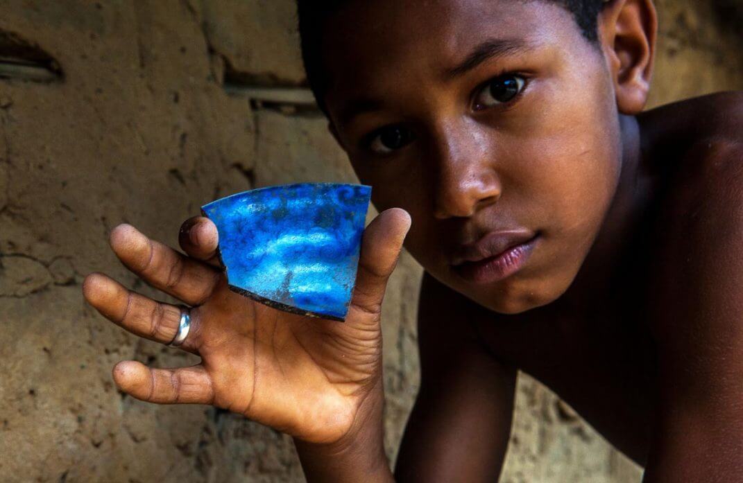 Garoto mostra resquícios de louça da antiga fazenda. Foto: Lilo Clareto/Repórter Brasil