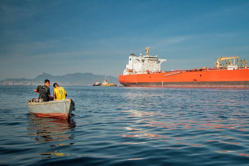 Barco de moradores locais em frente a navio petroleiro. Foto: Marcio Isensee e Sá